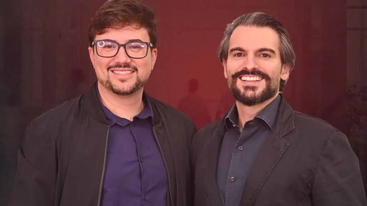 Rômulo Oliveira y Ygor Minassa, fundadores de PS Zerado, posan frente a la identidad visual del congreso.