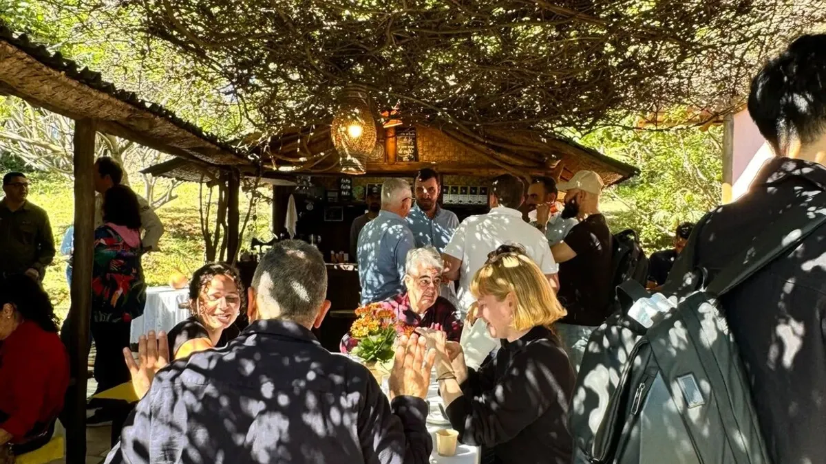 Participantes de Coffee LATAM 2026 conversan durante la visita de campo en una finca cafetera.