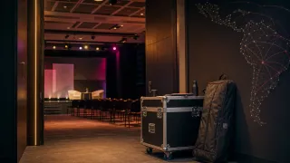Auditorio preparado para una conversación con estuche de producción y rutas visuales que representan la circulación regional de speakers.