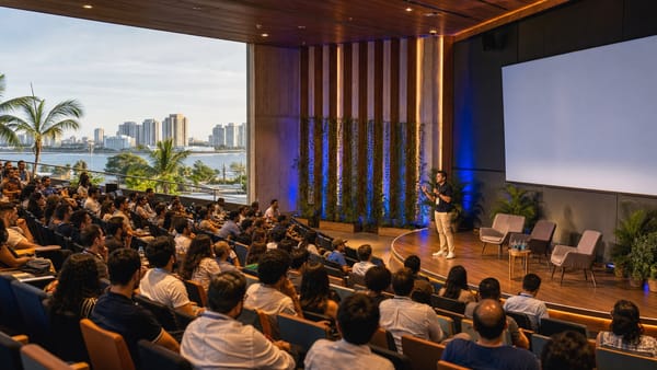 Audiencia reunida frente a una conferencia tecnológica en un auditorio de inspiración caribeña.
