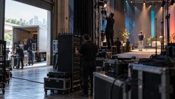 Un equipo coordina transporte, carga técnica, iluminación y prueba de sonido durante el montaje de un evento corporativo.