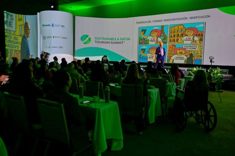 Audiencia escucha una ponencia en el Sustainable and Social Tourism Summit, en una sala con iluminación verde.